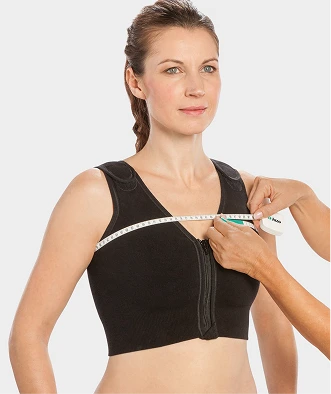 Female model standing while someone measures her bust size for a custom-made compression garment.